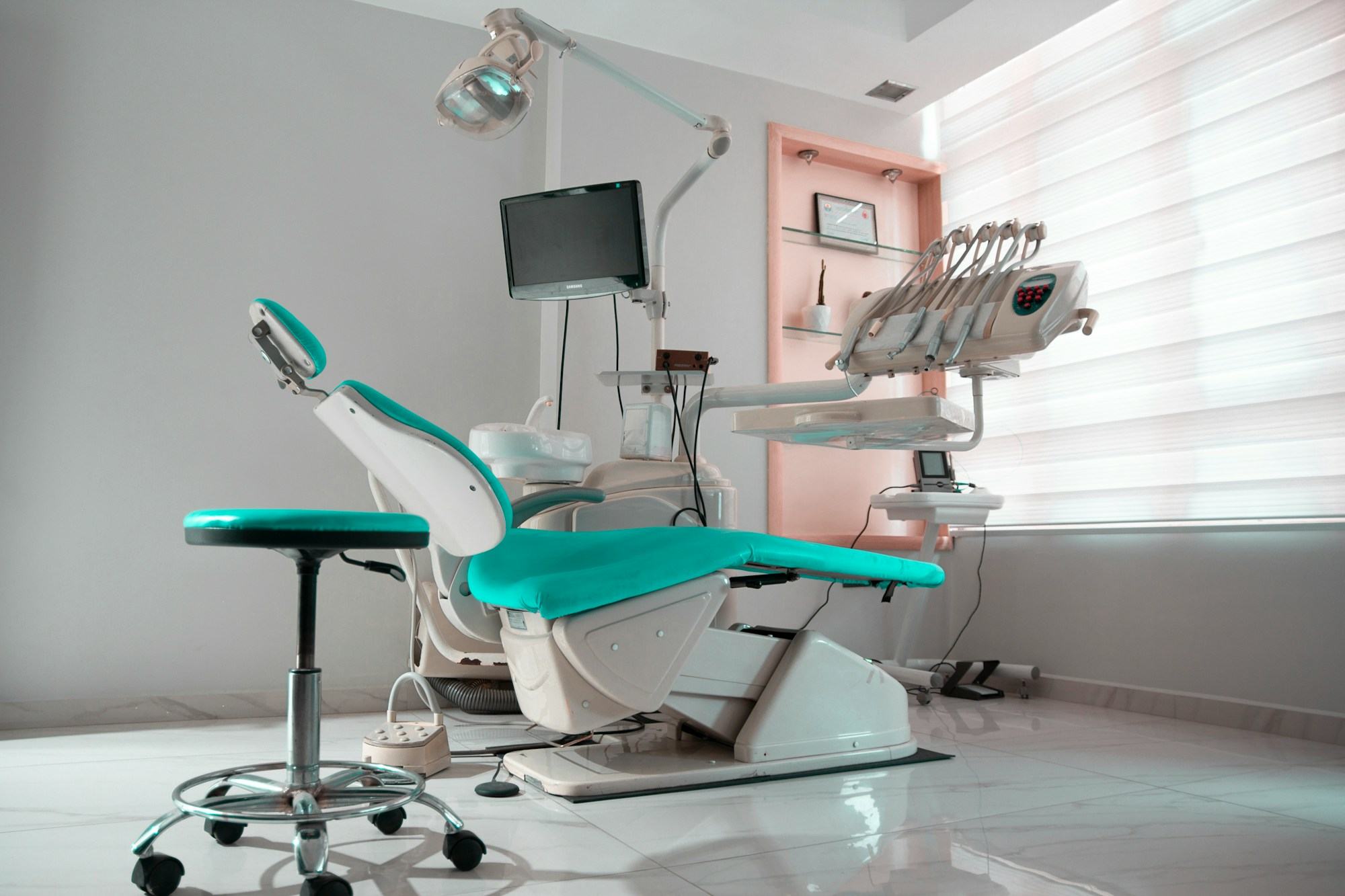 Consultorio odontológico luminoso con silla turquesa y lámpara dental