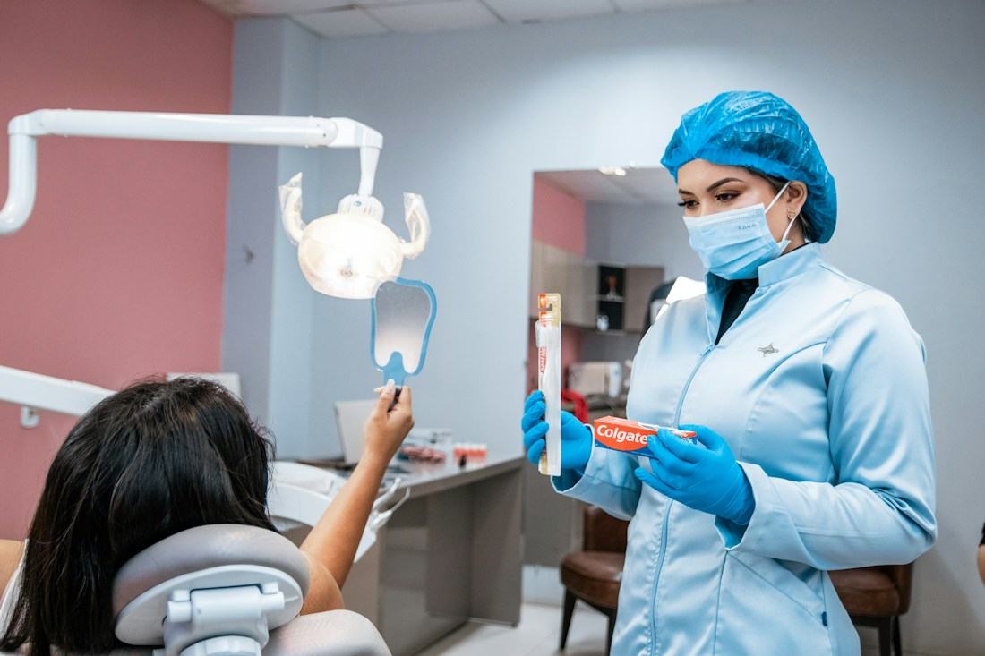Odontóloga enseñándole a una niña a cepillarse con un modelo dental